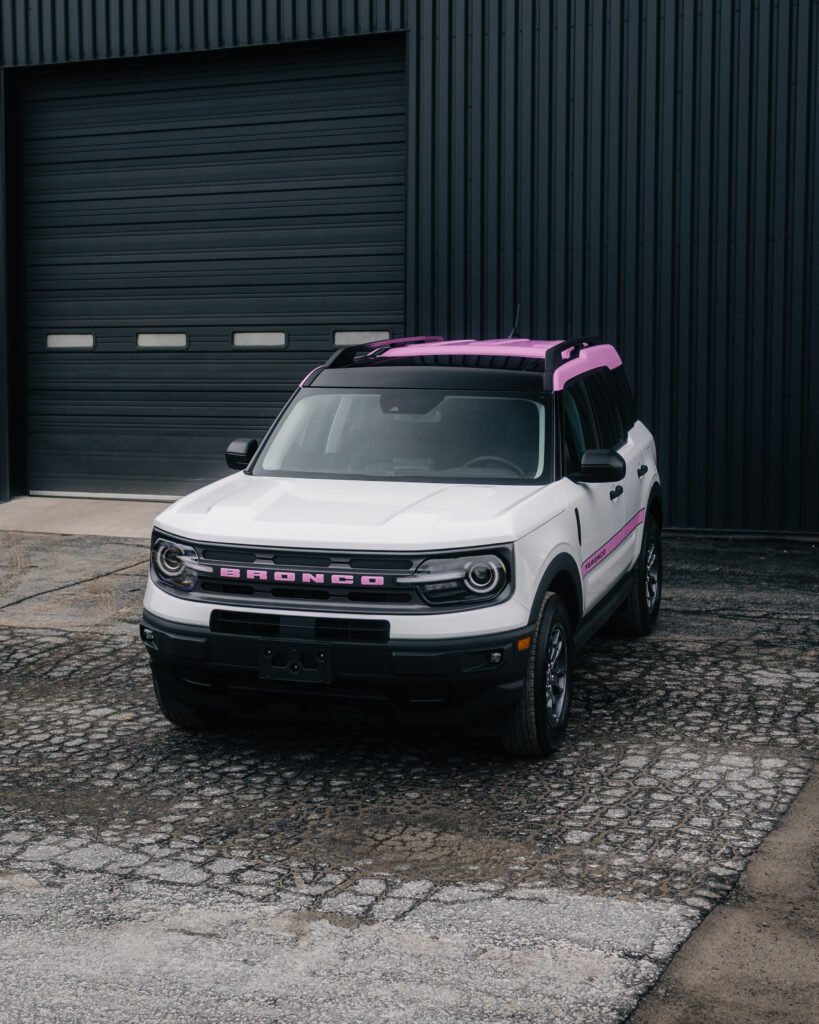 Front view of a Ford Bronco Sport with custom pink accents parked outside a detailing studio.